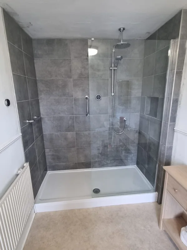 Large walk-in shower with a low-profile tray, grey tiled walls and a clear glass screen